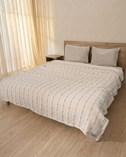 Neatly made bed with beige bedding in a bedroom setting