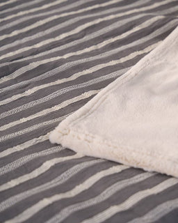 Close-up of a gray and white striped fabric with a textured white border.