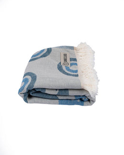 Folded towel with blue and gray pattern and white fringe on a white background