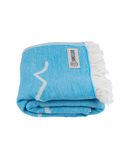 Folded blue towel with white fringe and a visible brand label on a white background