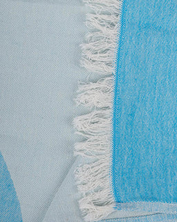 Close-up of a blue fabric with white fringe on a light blue background