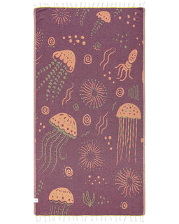 A maroon beach towel with a marine life design, including jellyfish and sea anemones, with twisted tassels at the bottom.