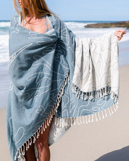 Person holding a blue and white patterned towel on a beach