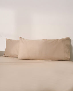 Beige pillowcases on a beige bed against a plain background