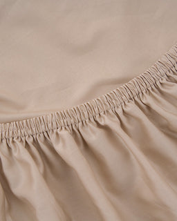 Close-up of beige fitted sheet with elastic waistband