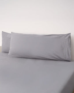 Gray pillowcases on a bed with a plain background
