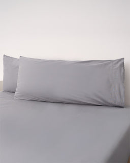 Gray pillowcases on a bed with a plain background
