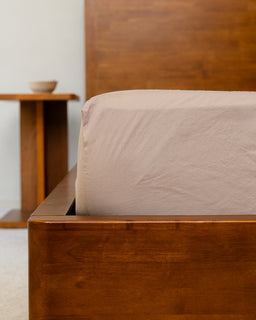 Wooden bed frame with a brown headboard and matching footboard, featuring a beige mattress.