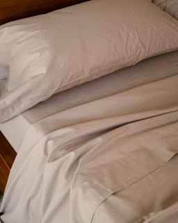 Beige bedding with a pillow on a bed