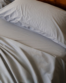 Close-up of grey bedding with a pillow and blanket