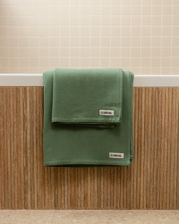 Green towel with a brand label on a wooden surface