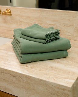 Stack of green towels on a wooden surface