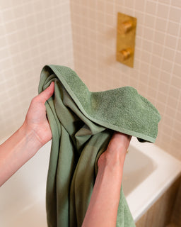 Person holding a green towel in a bathroom setting