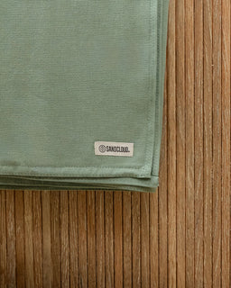 Green fabric with a Sandcloud label on a wooden surface