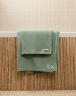 Green towel with a brand label on a wooden surface