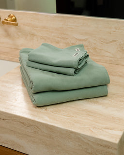 Stack of green towels on a wooden surface