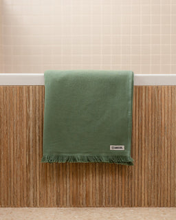 Green towel with a brand label on a wooden surface