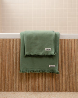 Green towel with a brand label on a wooden surface