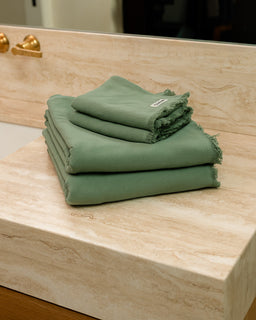 Stack of green towels on a wooden surface