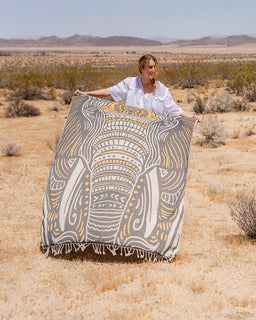 Person holding a patterned towel in a desert landscape