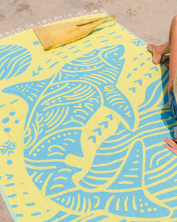 Beach towel with shark design on a sandy surface