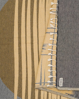 Textile with striped pattern and tassel details on a gray background