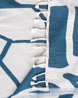 Close-up of a blue and white patterned fabric with a zigzag edge.