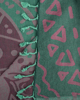Close-up of a fabric with geometric patterns and green tassels.