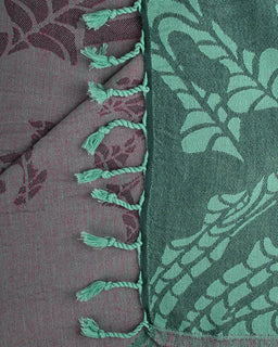 Close-up of two-sided patterned towel with tassels on a textured background