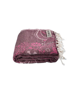 Folded purple towel with white floral patterns and tassels on a white background