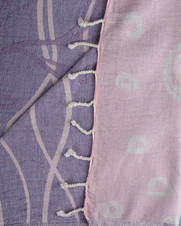 Close-up of a purple and pink fabric with geometric patterns and tassels.