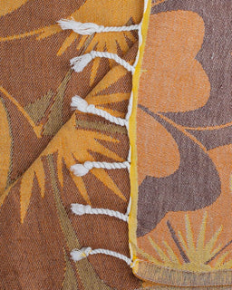 Close-up of a woven fabric with leaf patterns in brown, orange, and yellow.