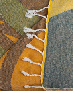 Close-up of a colorful fabric with tassels and geometric patterns.