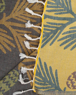 Close-up of a fabric with leaf pattern and tassels on a yellow background