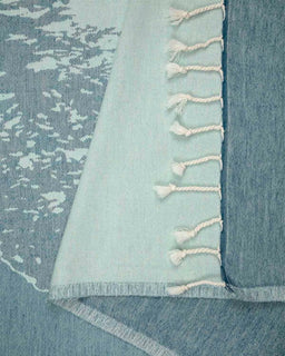 Close-up of a textured fabric with tassels in a blue and white color scheme.