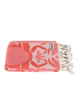 Folded pink towel with white crab pattern and tassels on a white background