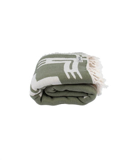 Folded green blanket with white patterns on a white background