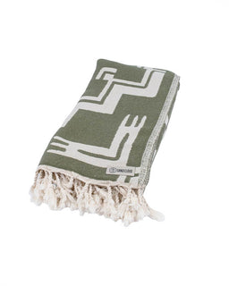 Green blanket with white geometric patterns and fringes on a white background