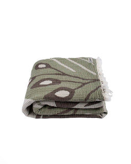 Folded green and brown patterned towel with white tassels on a white background