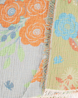 Close-up of a floral quilt with orange, blue, and green flowers on a textured fabric background.