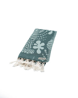 Green towel with floral pattern and white tassels on a white background