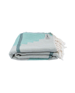 Folded towel with turquoise border and white tassels on a white background