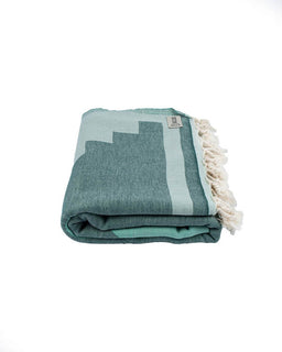 Folded teal and light blue towel with tassels on a white background