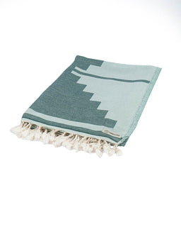Teal and white patterned towel with tassels on a white background