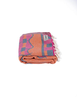 Folded towel with colorful pattern and tassels on a white background