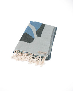 Folded towel with abstract design and brand label on a white background