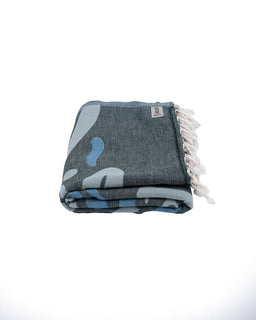 Folded gray towel with blue abstract design and white fringe on a white background