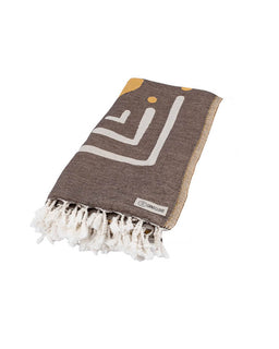 Brown towel with white geometric pattern and tassels on a white background