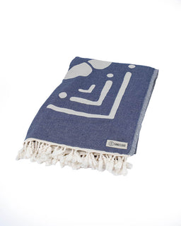 Blue towel with white geometric patterns and tassels on a white background