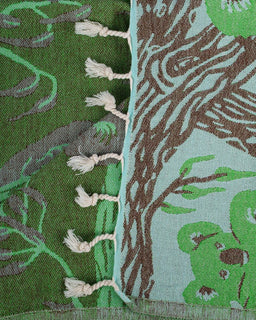 Close-up of a fabric with tree and animal pattern, featuring green, brown, and white colors.